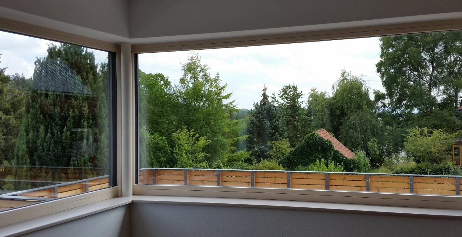 A large window with a view of trees and a balcony.