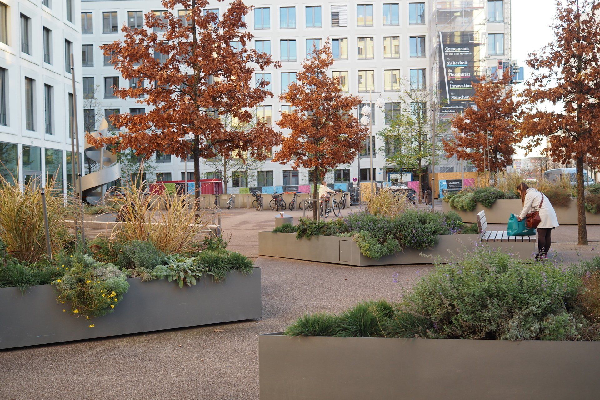 A woman is standing in a garden in front of a building.