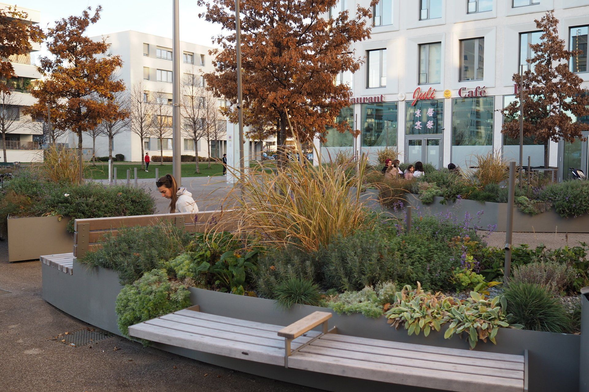 A man is sitting on a bench in a park surrounded by plants.
