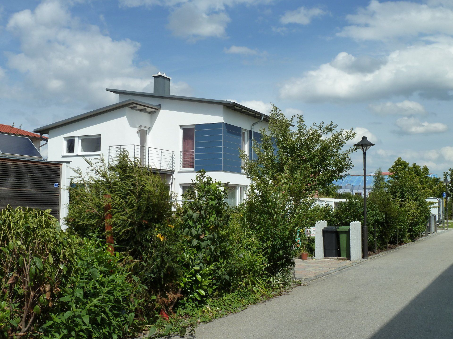A white house with blue shutters is surrounded by trees and bushes
