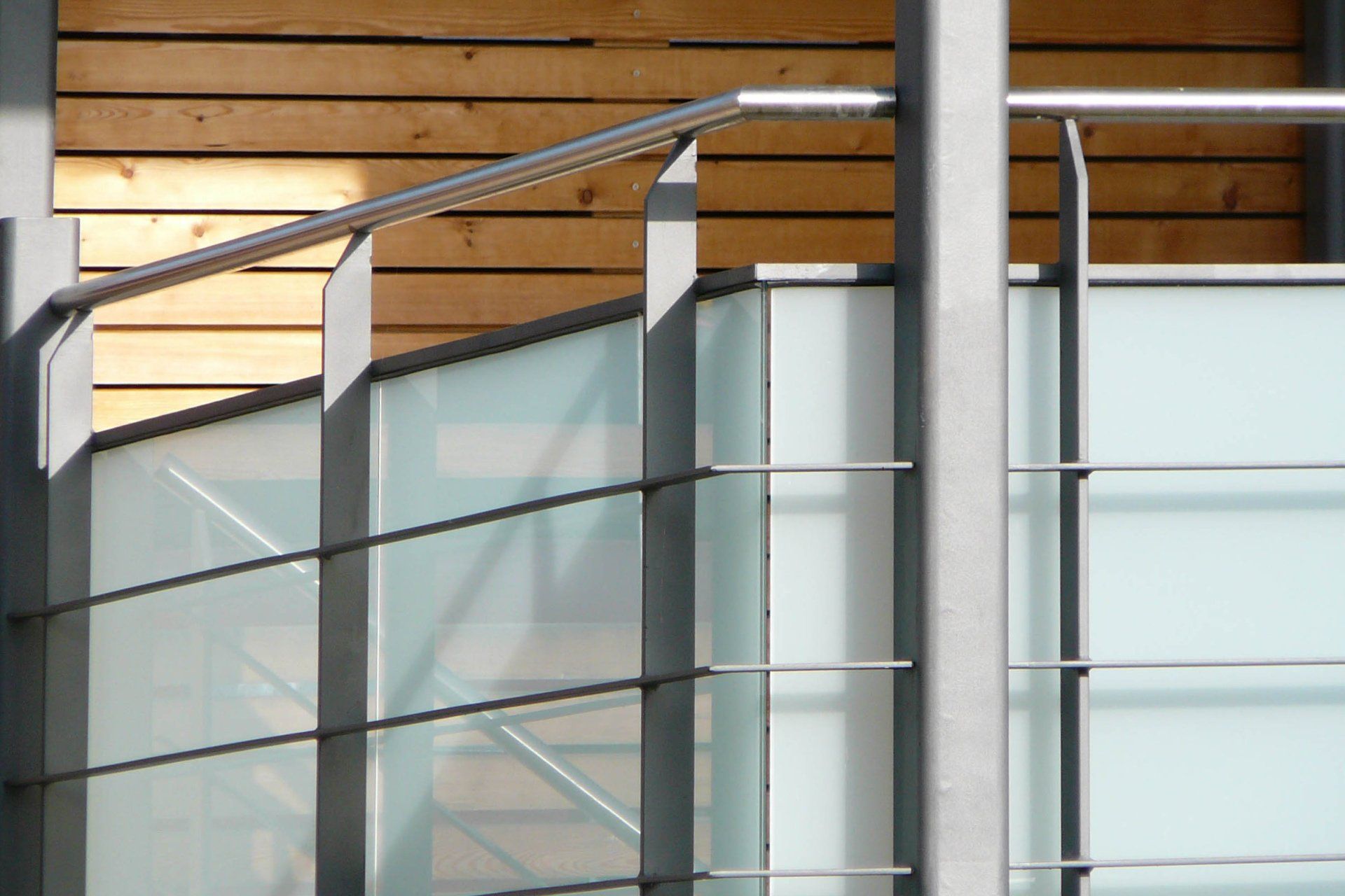 A staircase with a glass railing and a wooden wall behind it