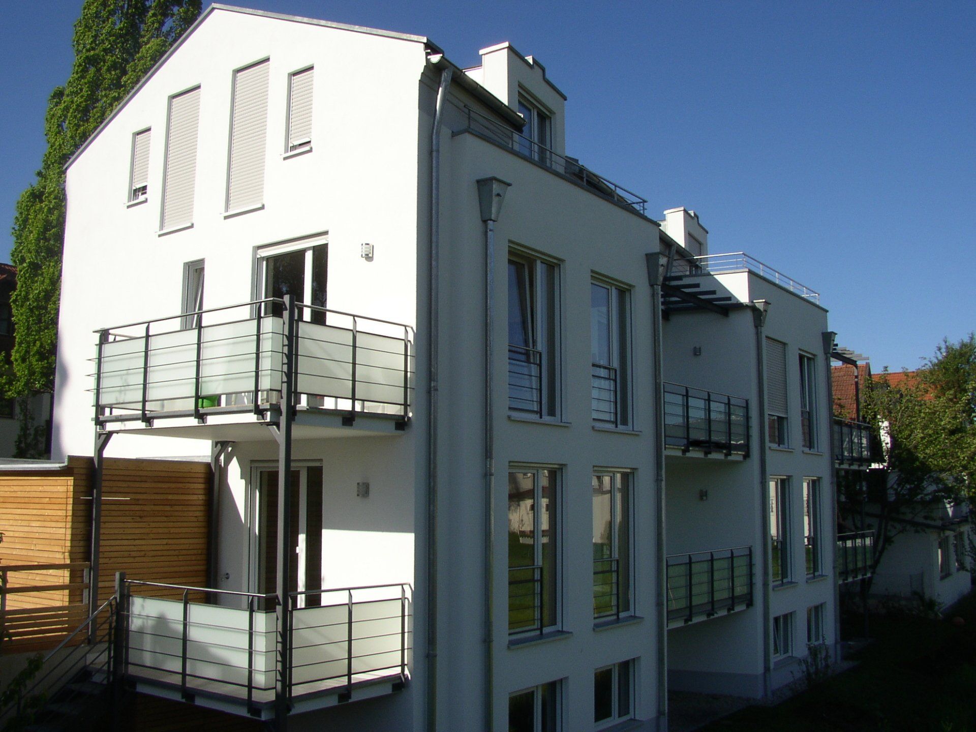 A white building with balconies and a blue sky in the background