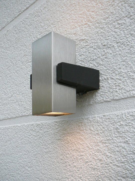 A stainless steel wall light is mounted on a white wall.