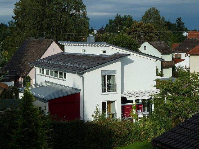 A white house with a red door is surrounded by other houses