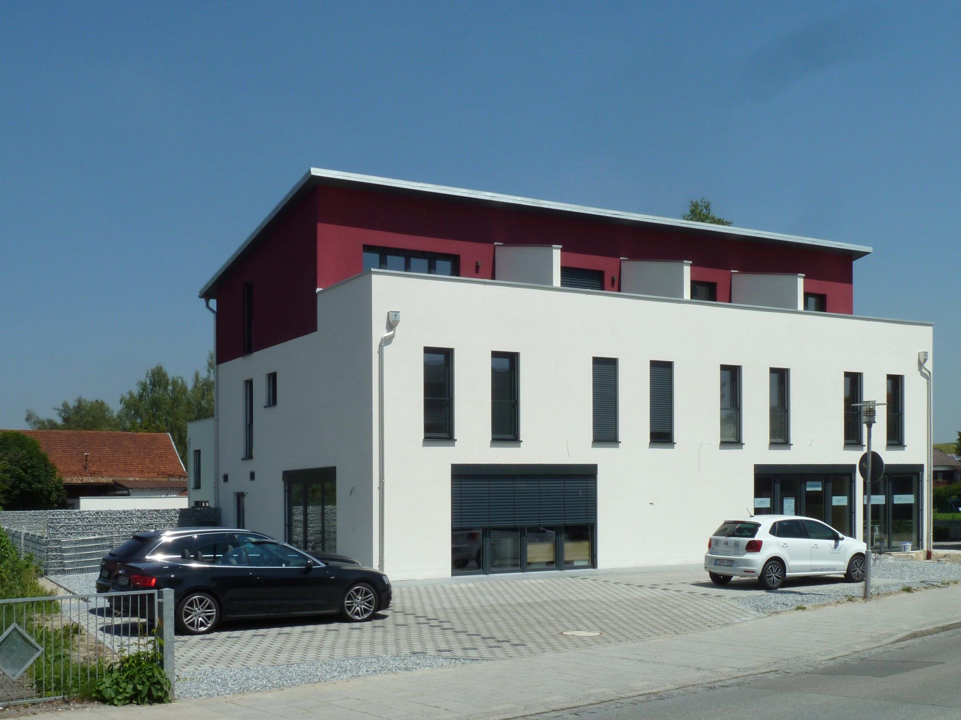 A black car is parked in front of a white building