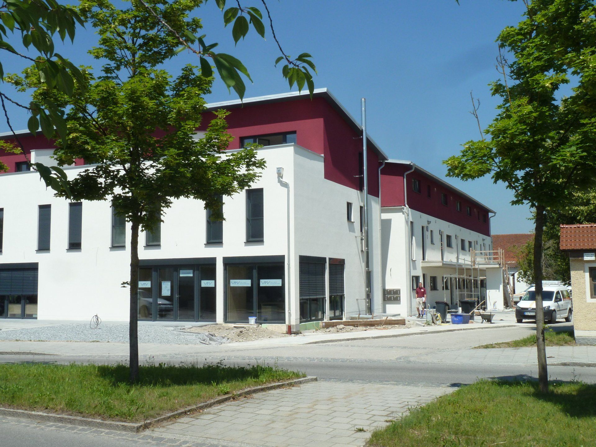 A white building with a red roof is under construction
