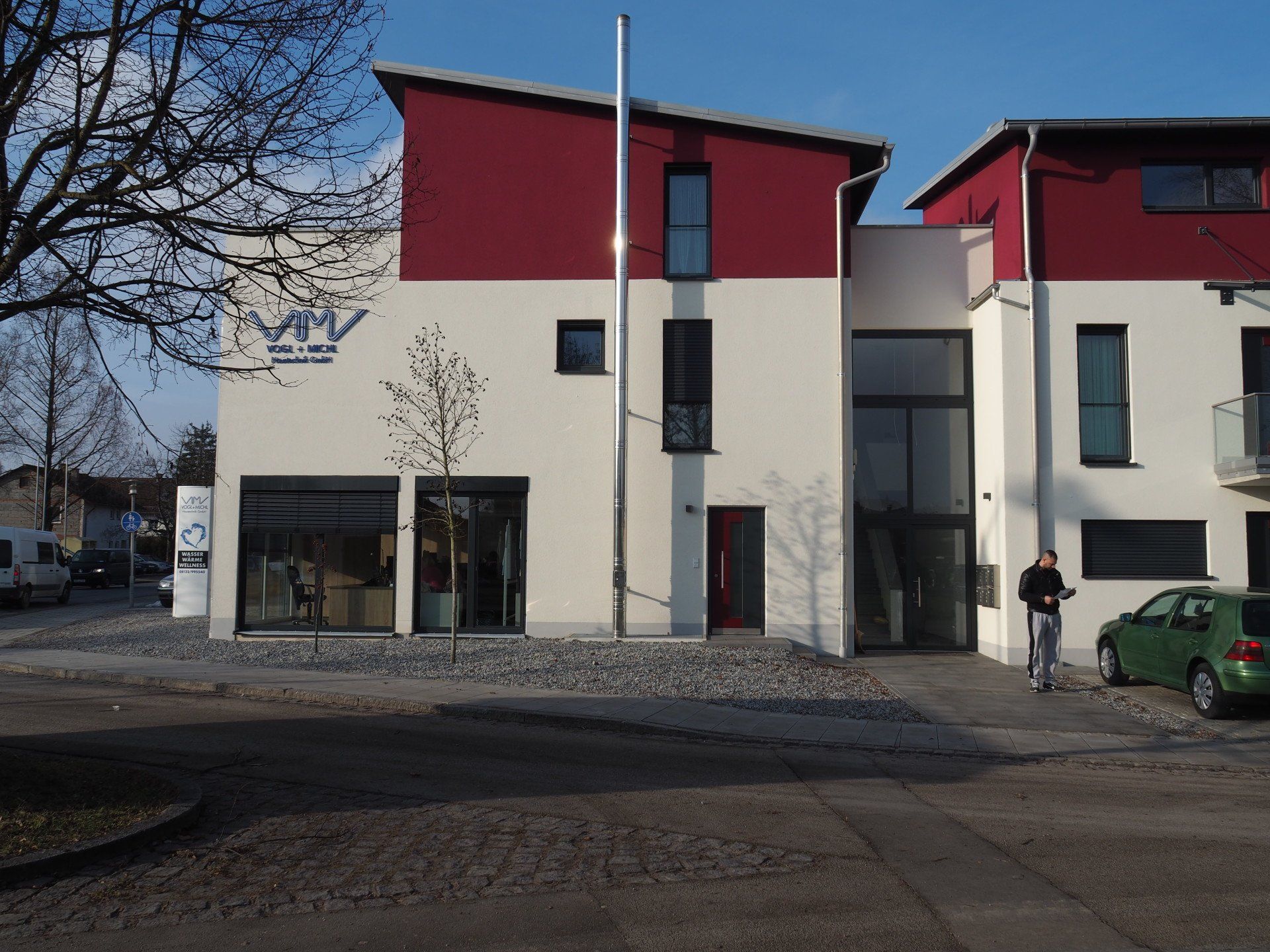 A white and red building with a green car parked in front of it