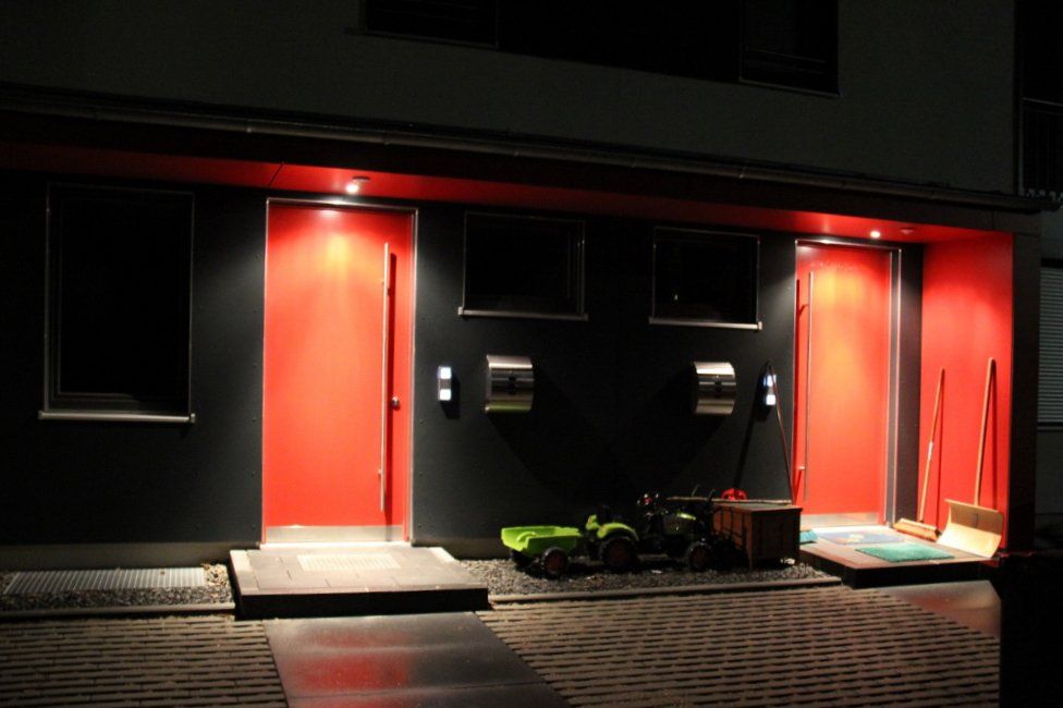 A green toy car is parked in front of a building with red doors