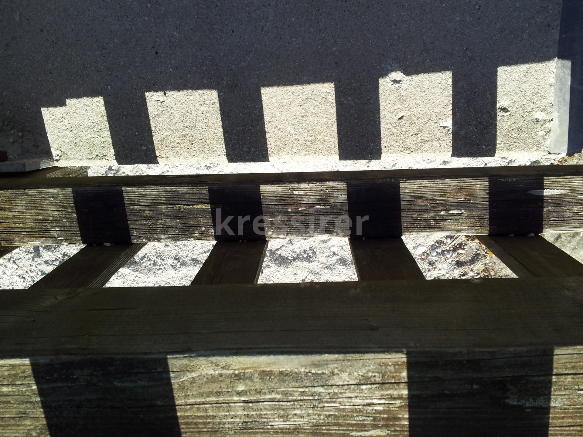 A shadow of a brick wall is cast on a wooden surface