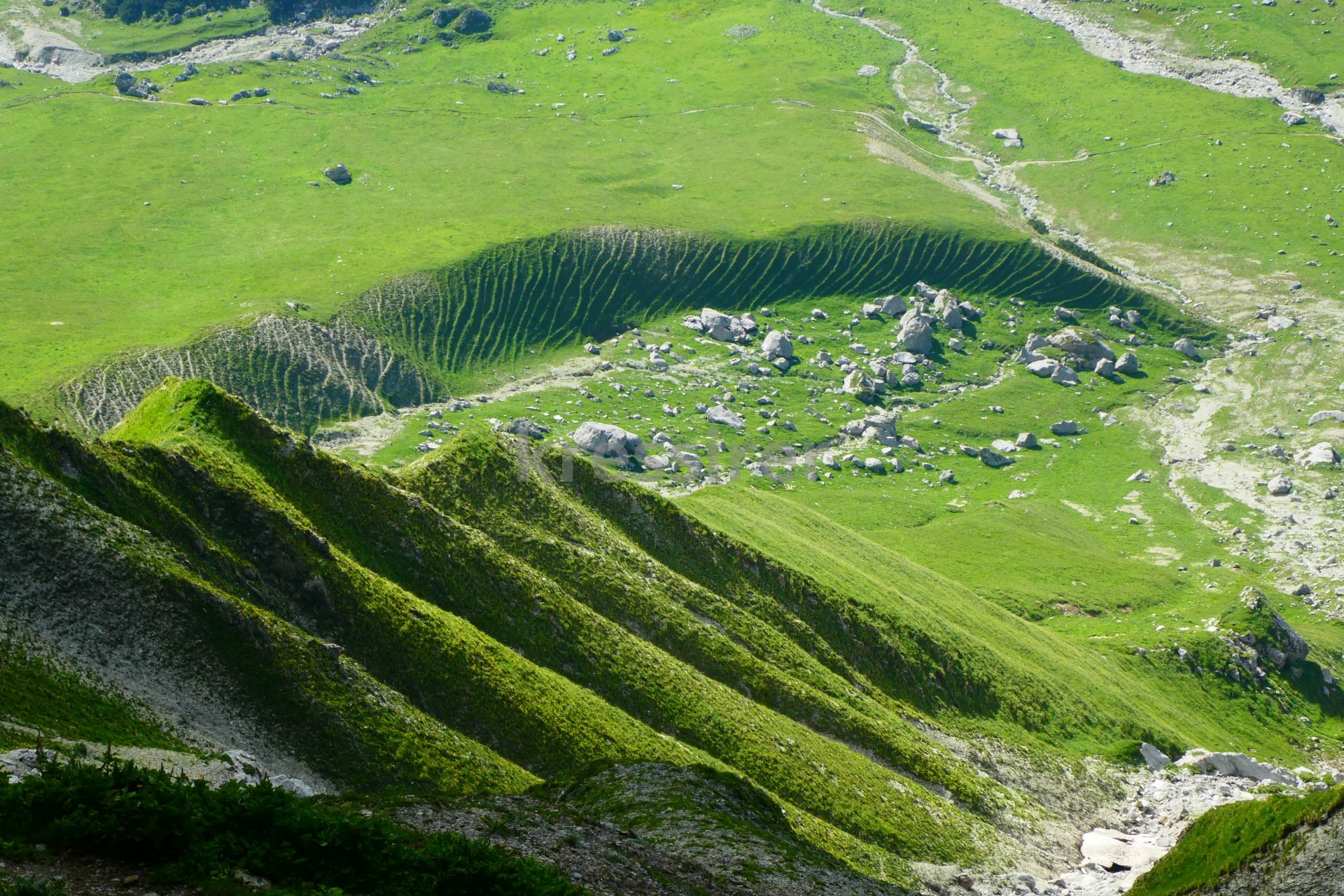 A lush green hillside with a river running through it