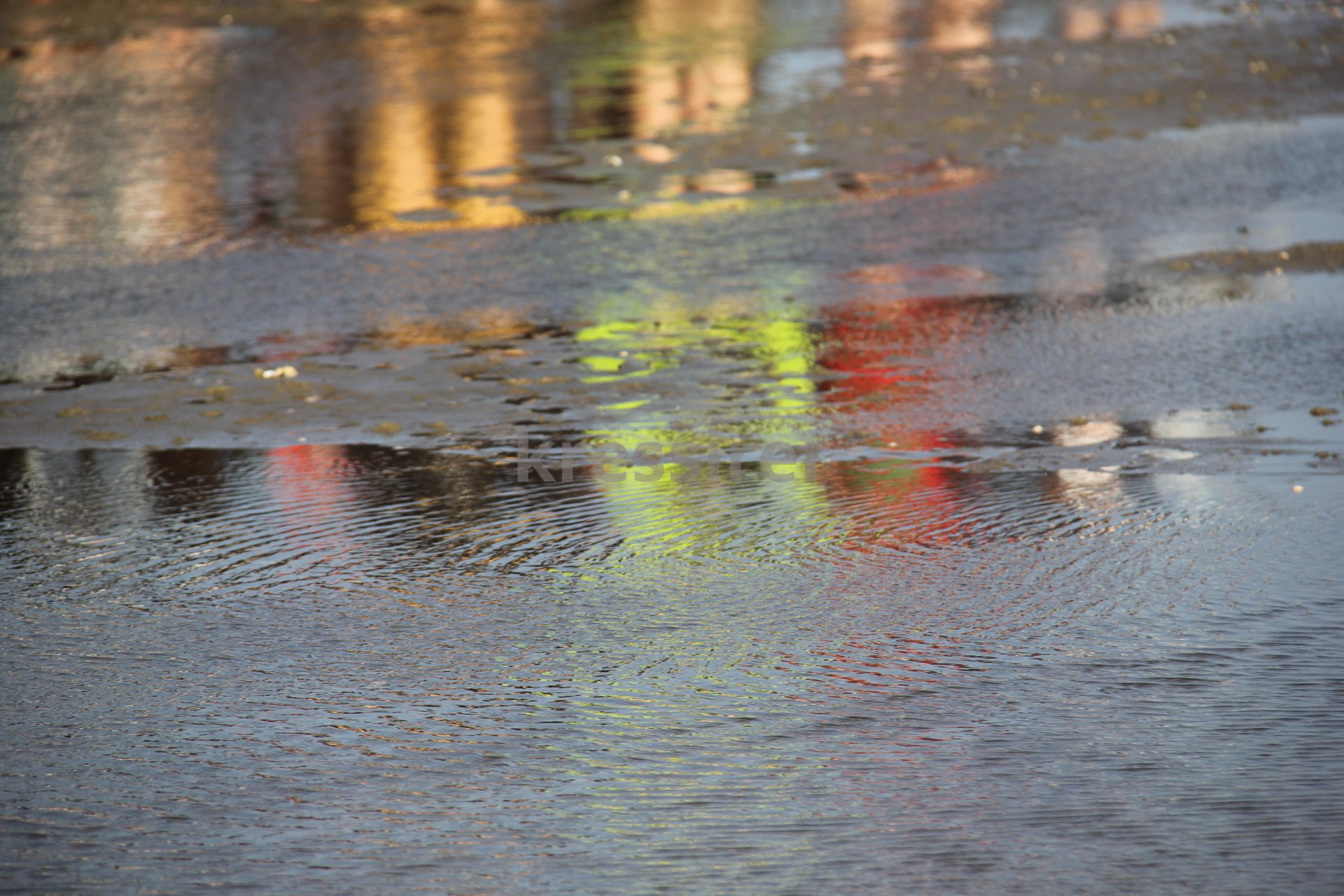 A puddle of water with a reflection of a building in it.