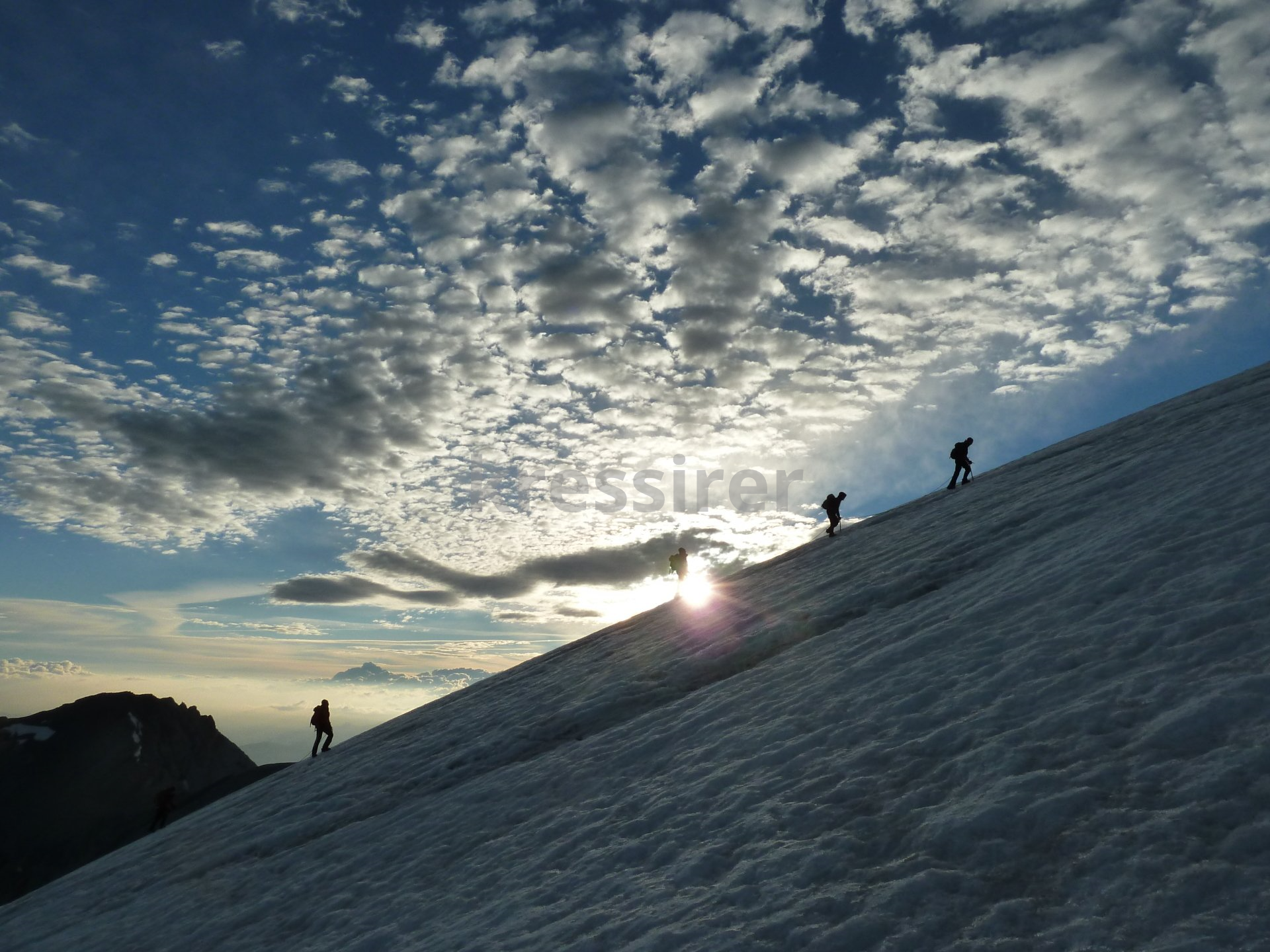 A group of people are walking up a snowy hill