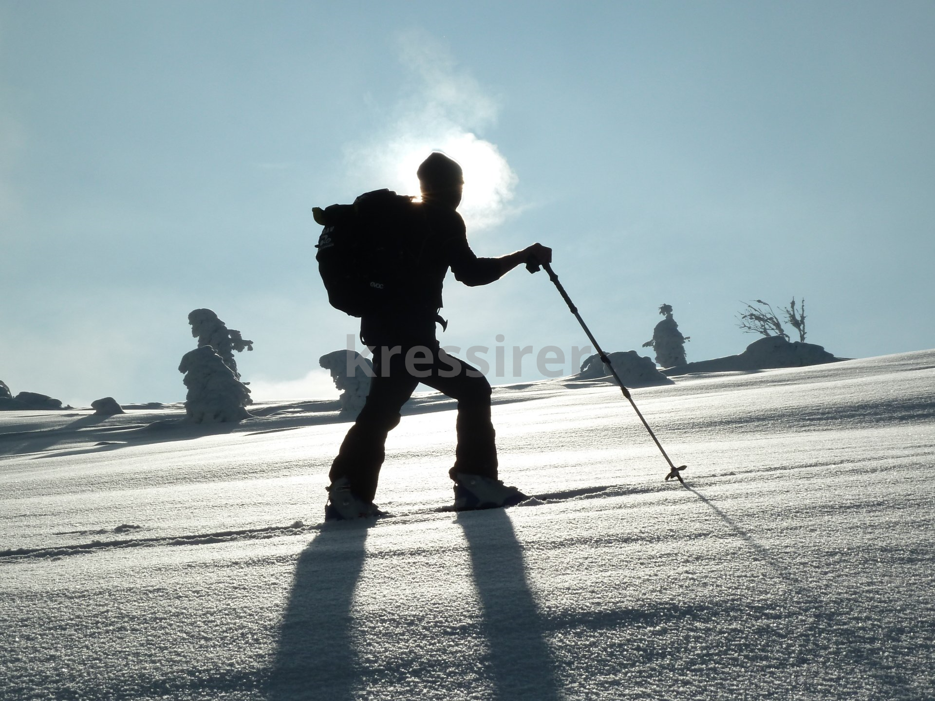 A silhouette of a person skiing down a snow covered slope