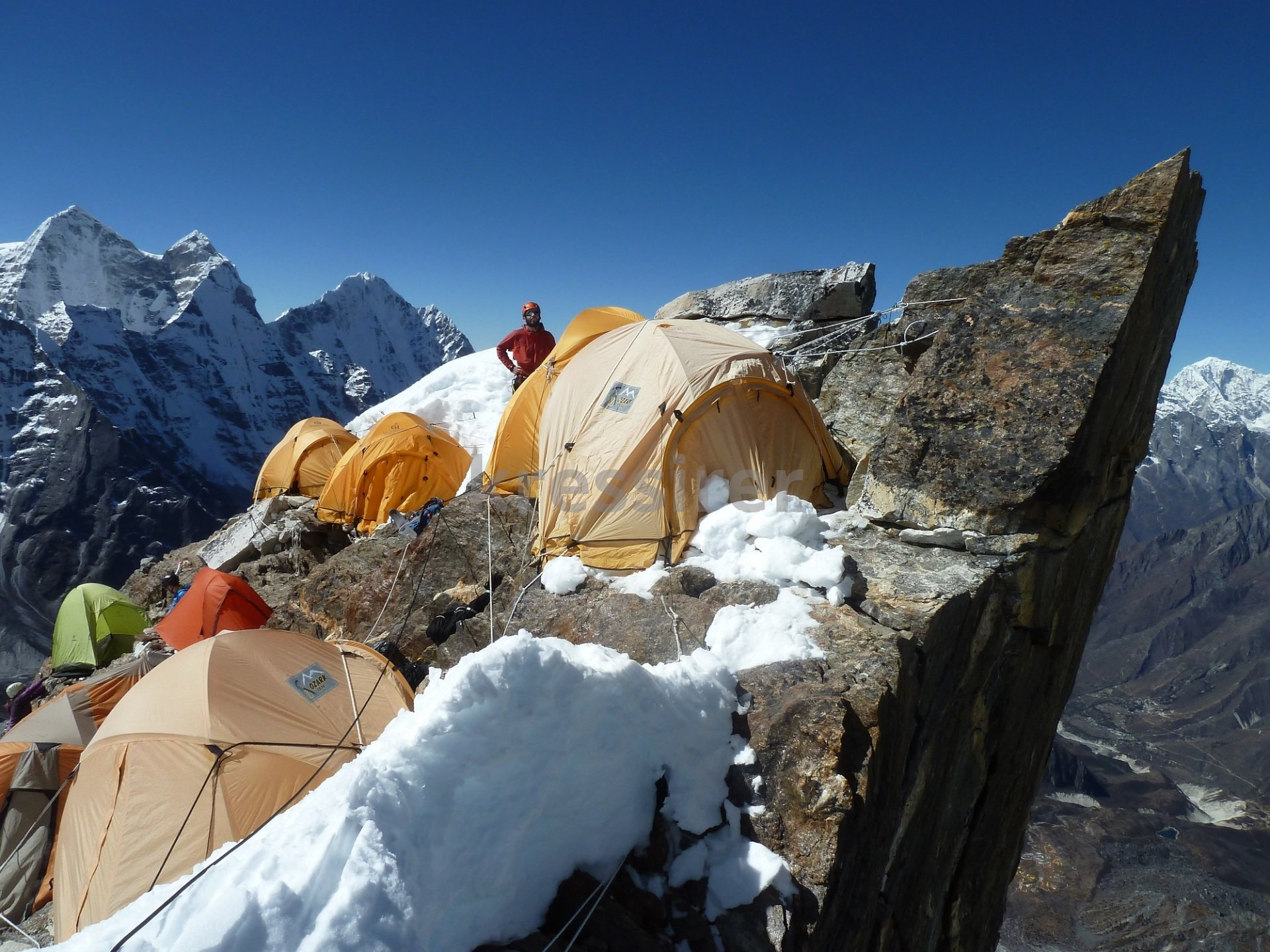A group of tents are sitting on top of a snow covered mountain