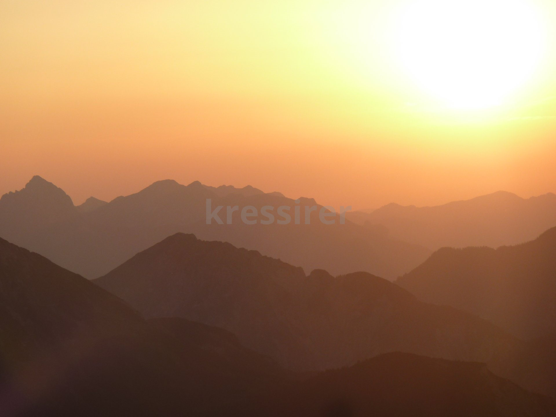 The sun is setting over the mountains in the distance.