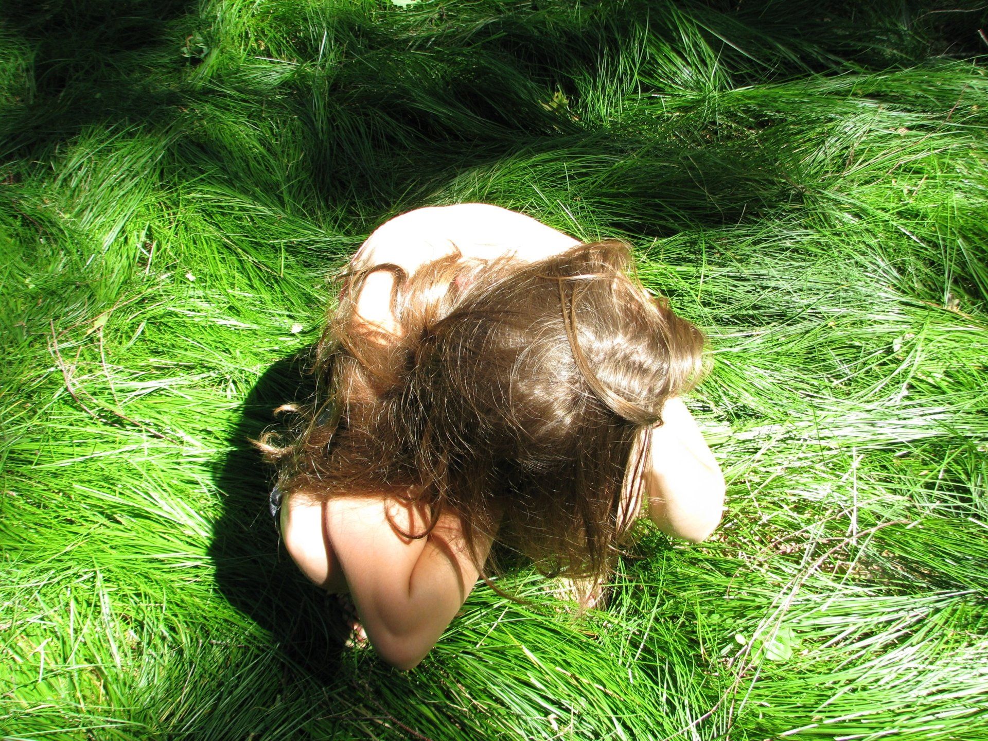 A woman is kneeling down in a field of tall grass