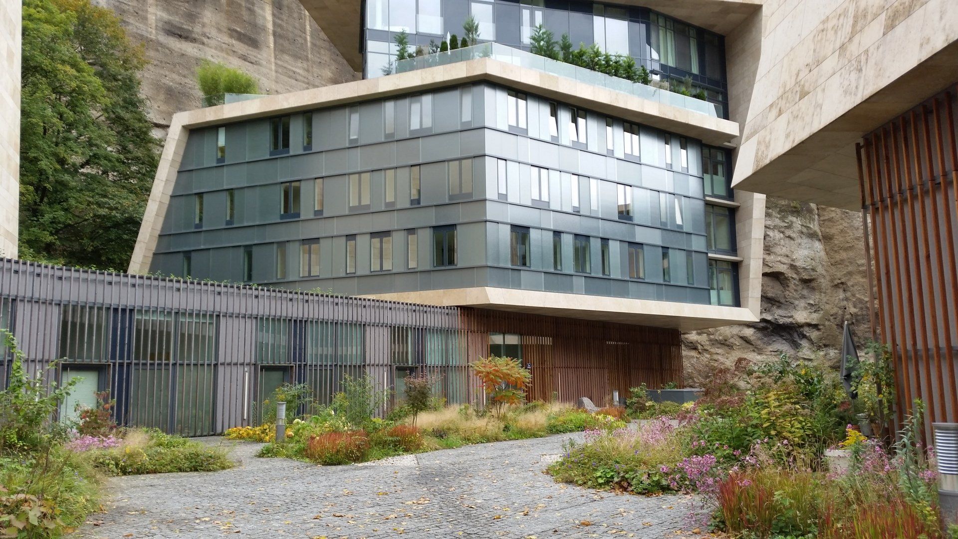 A large building with a lot of windows is surrounded by a lush green garden.
