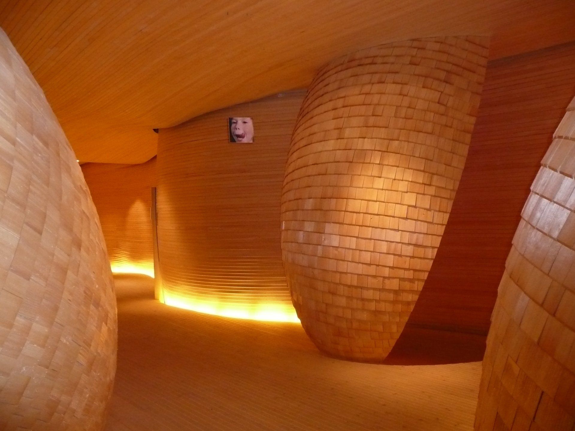 A hallway with brick walls and a mask on the wall