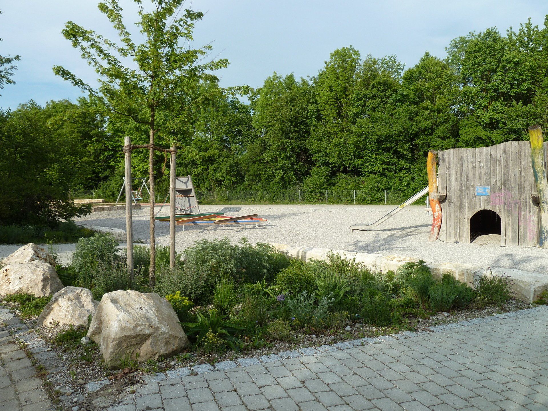 A brick walkway leads to a playground with trees in the background