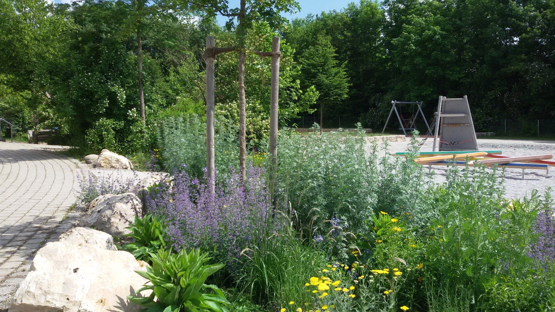A garden with flowers and trees and a playground in the background