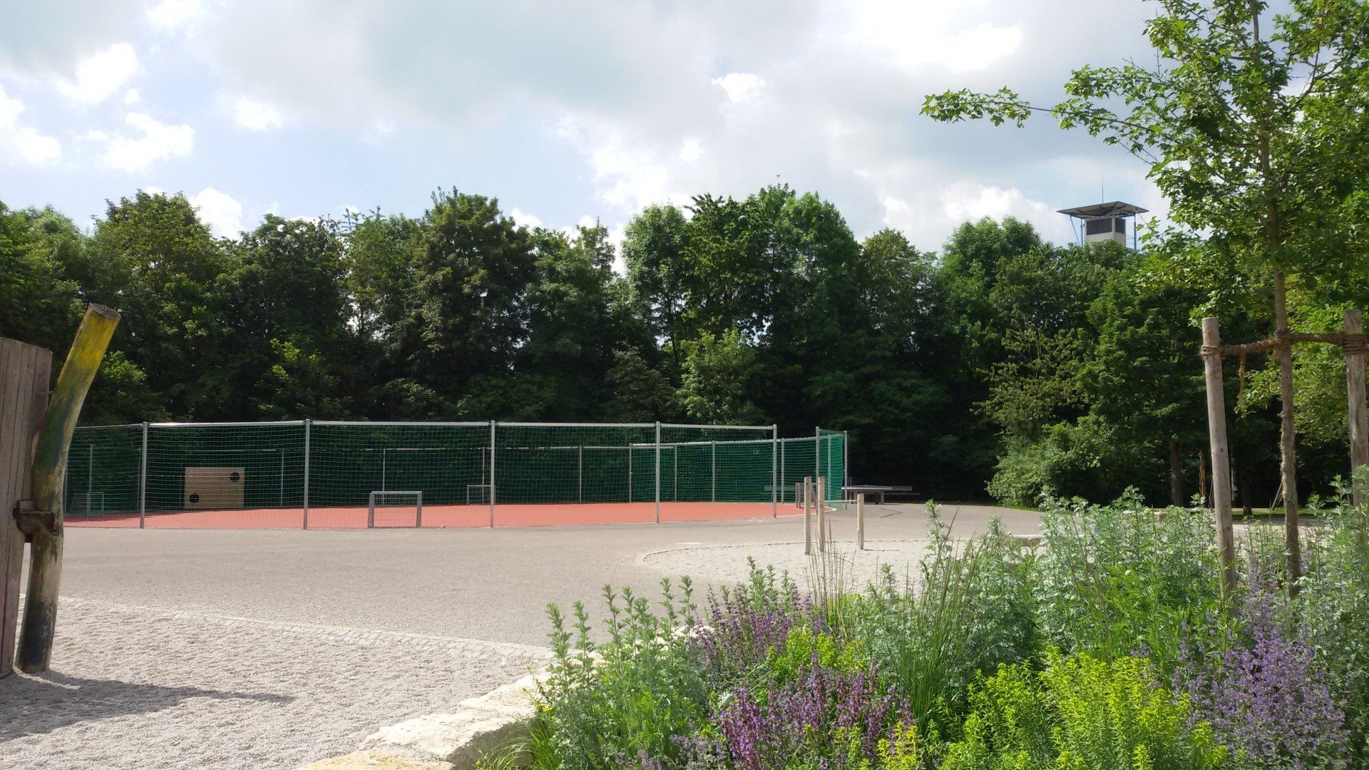 A soccer field is surrounded by trees and flowers