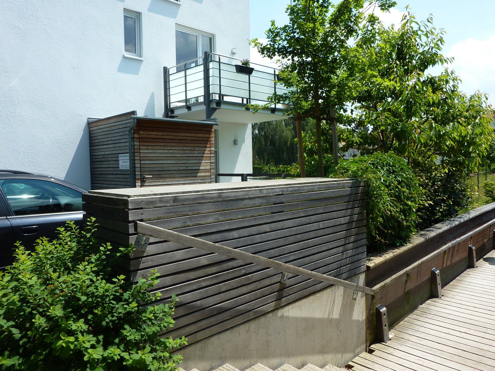 A black car is parked in front of a white building