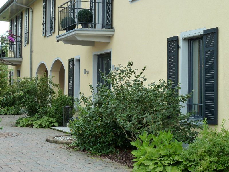 A yellow building with black shutters and a balcony