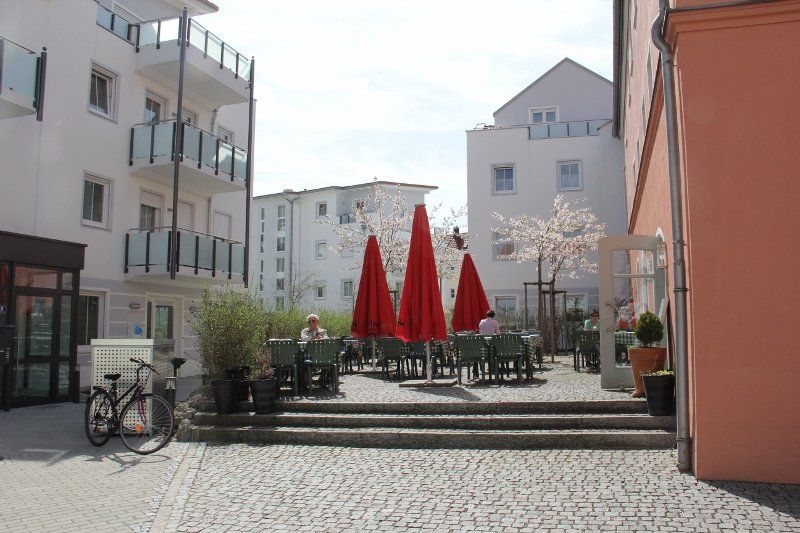 A bicycle is parked in front of a building with red umbrellas