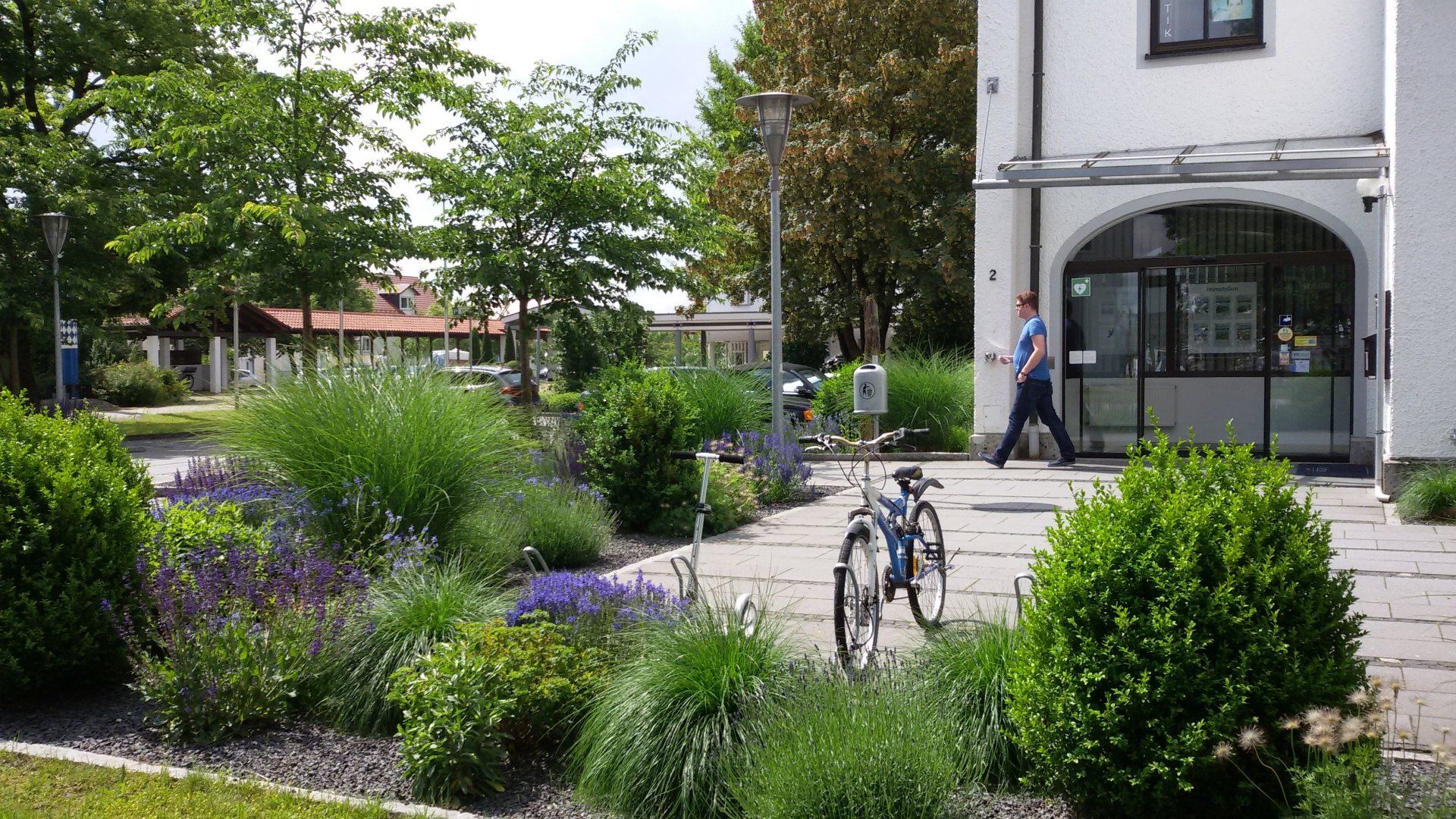 A man is walking in front of a building with a bicycle parked in front of it.