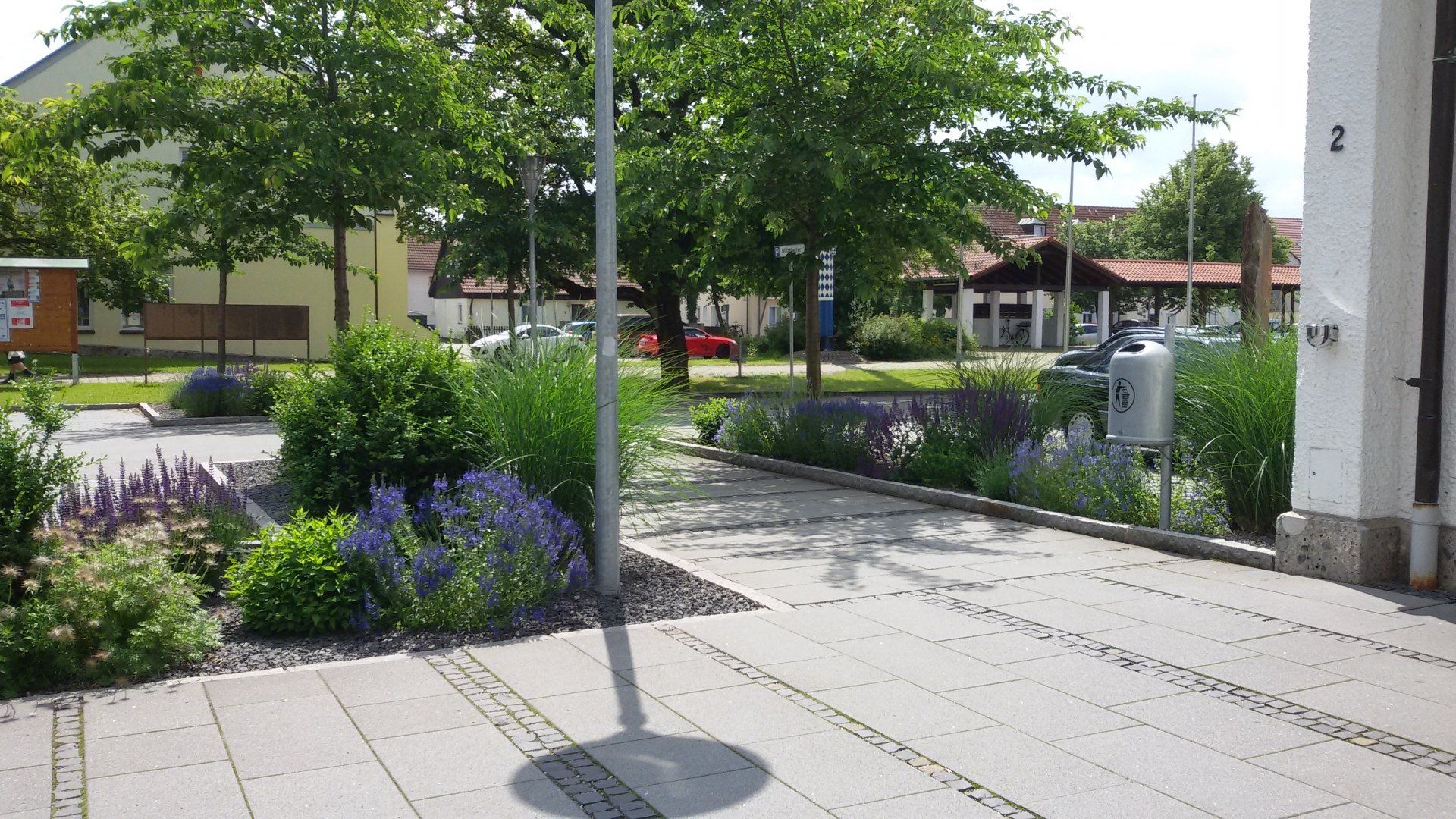 A shadow of a pole is cast on a brick walkway