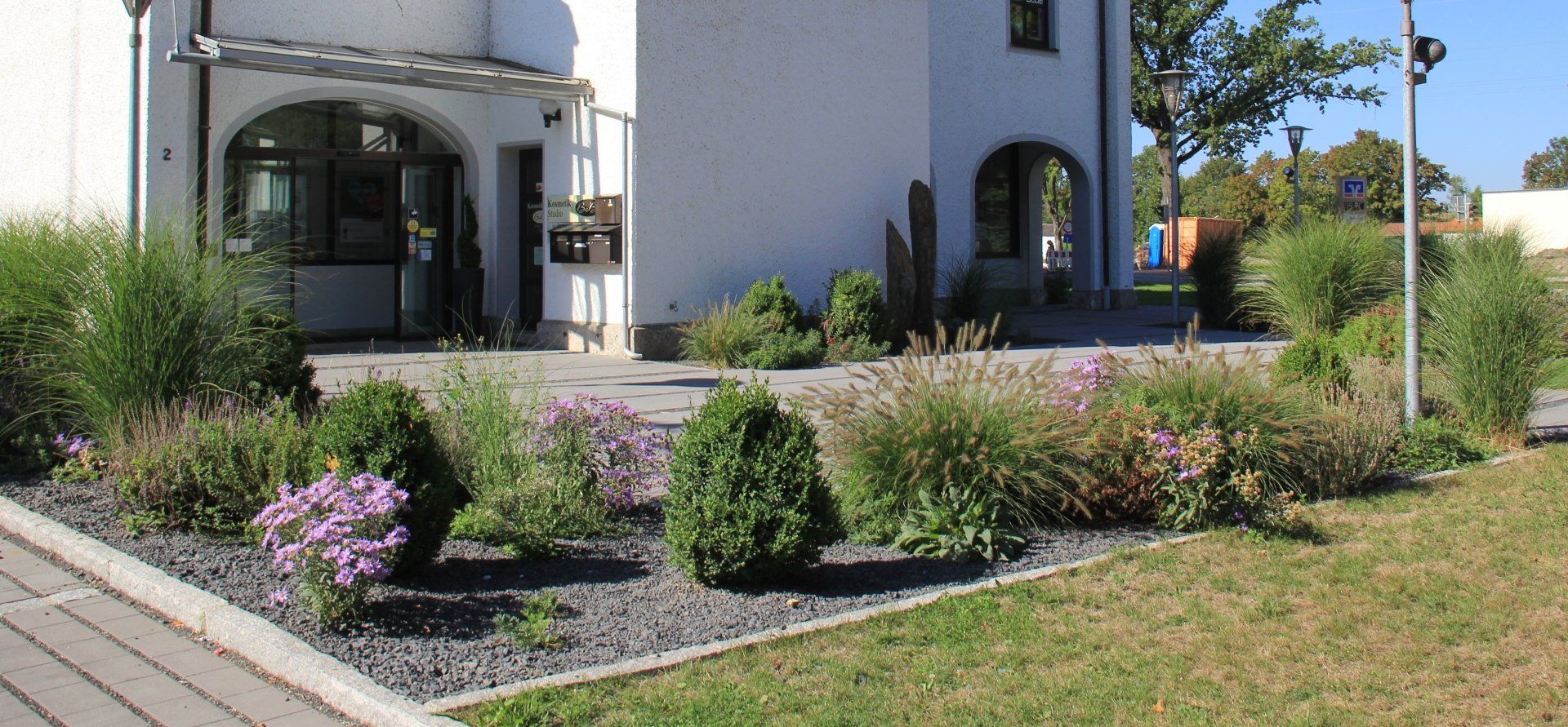 A white house with a garden in front of it.