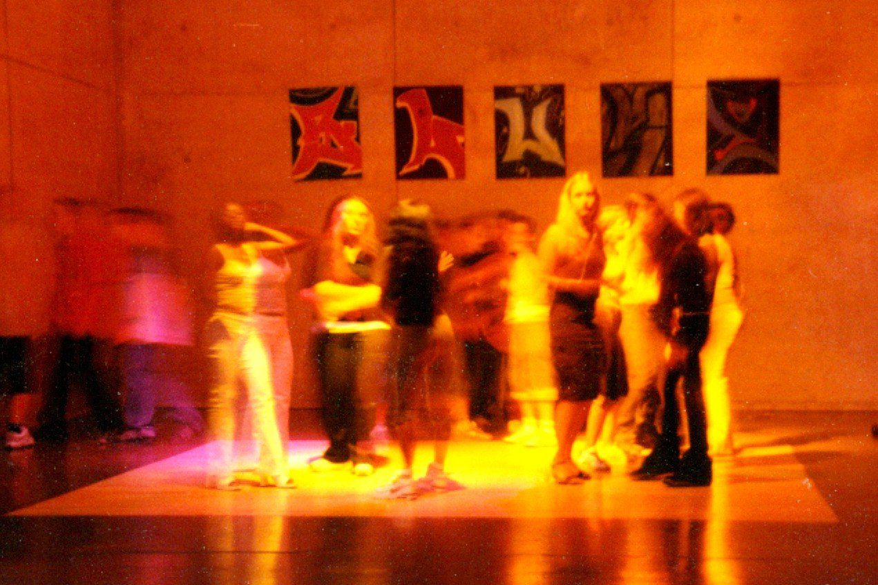 A group of people are standing in a room with paintings on the wall