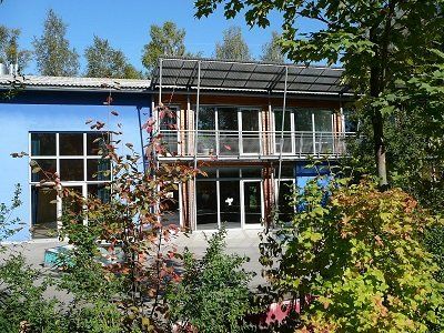 A blue building with a lot of windows is surrounded by trees