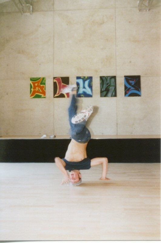 A person is doing a handstand in front of a wall with paintings on it