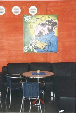 A room with a table and chairs and a painting on the wall