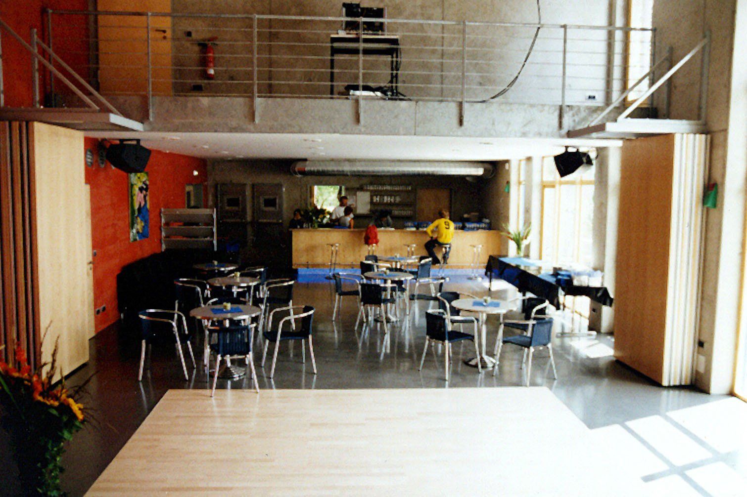 A large room with tables and chairs and a balcony