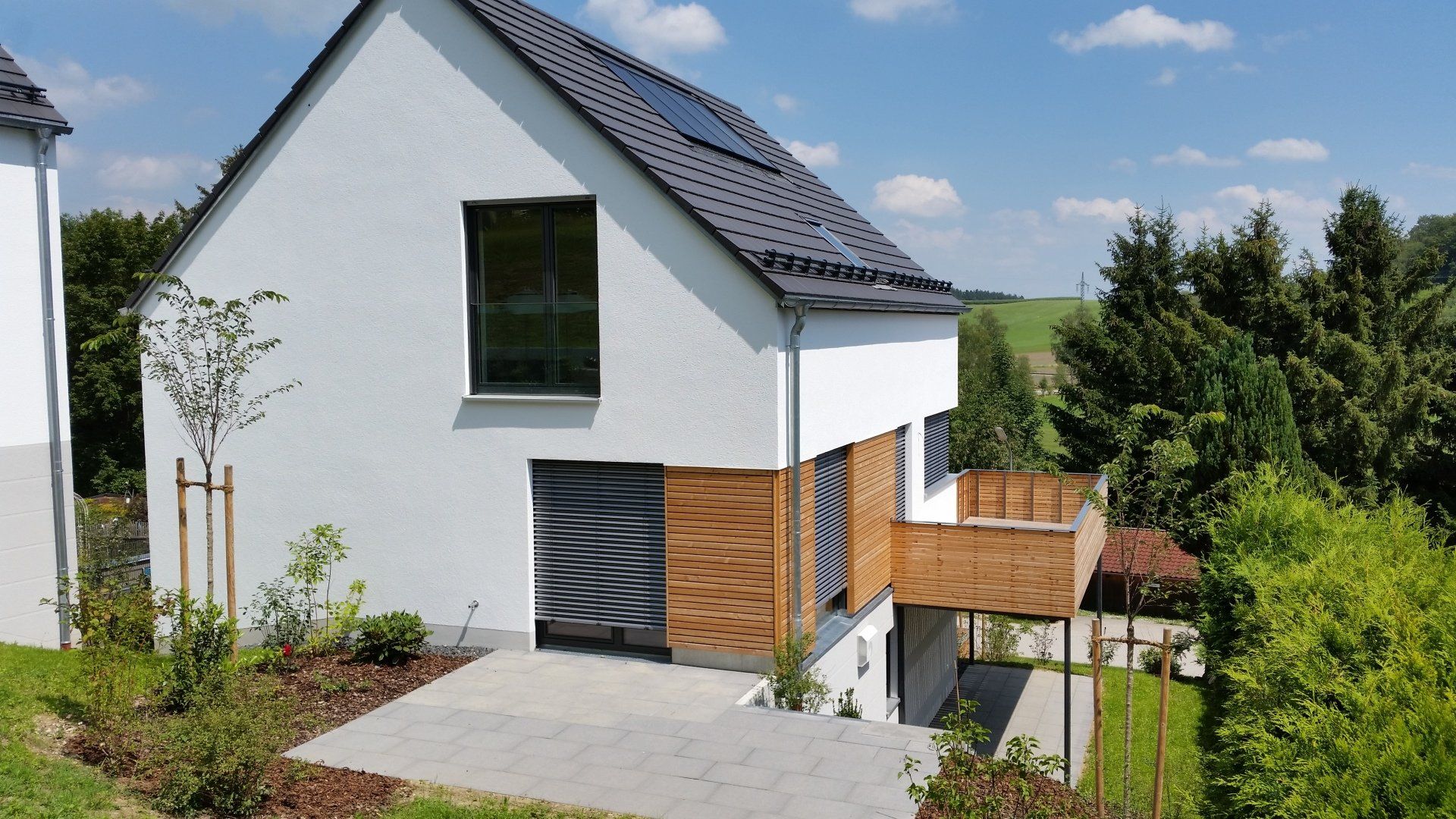 A white house with a black roof and a wooden deck