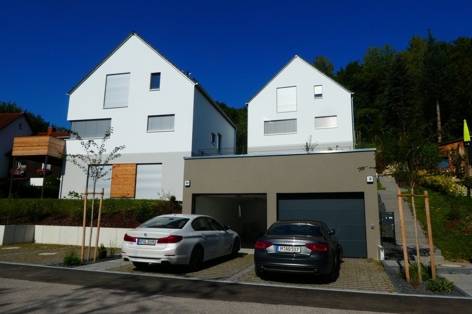 Two cars are parked in front of a white house