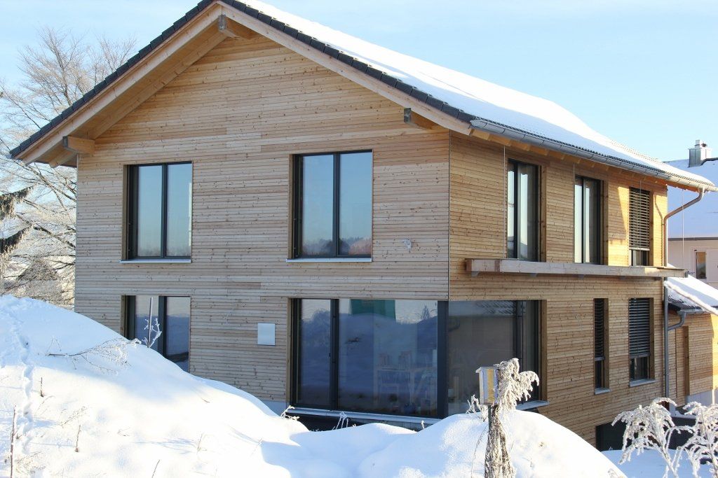 A wooden house with snow on the ground in front of it