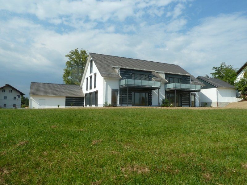 A large white house sits in the middle of a grassy field