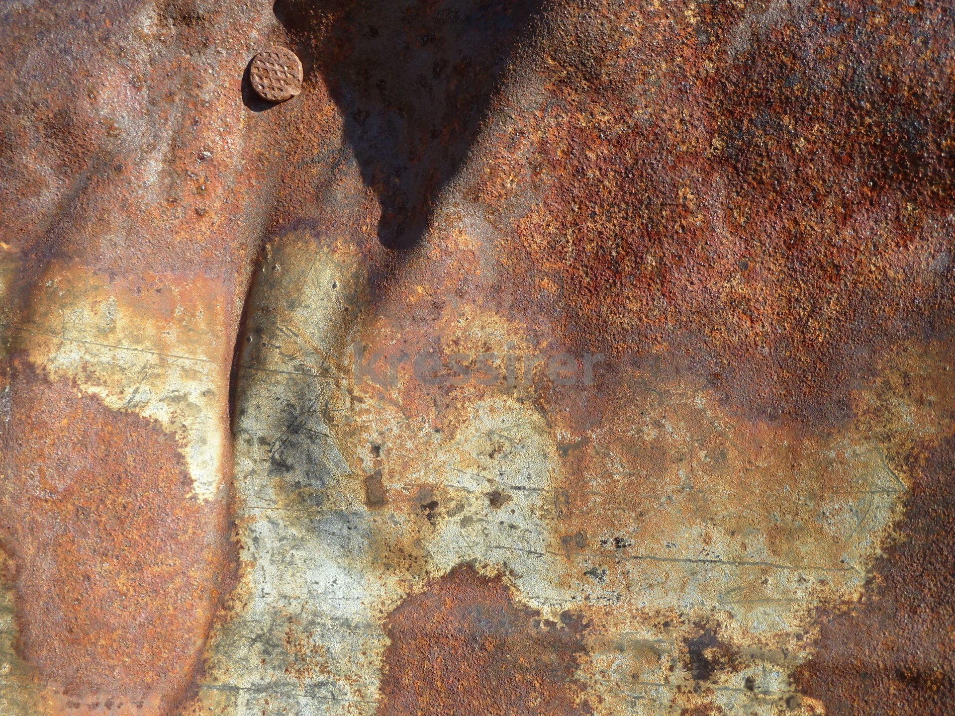 A close up of a rusty metal surface with a nail in it.
