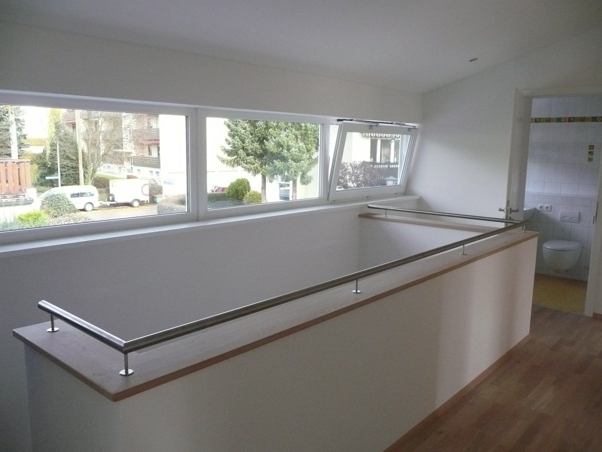 An empty room with a large window and a railing