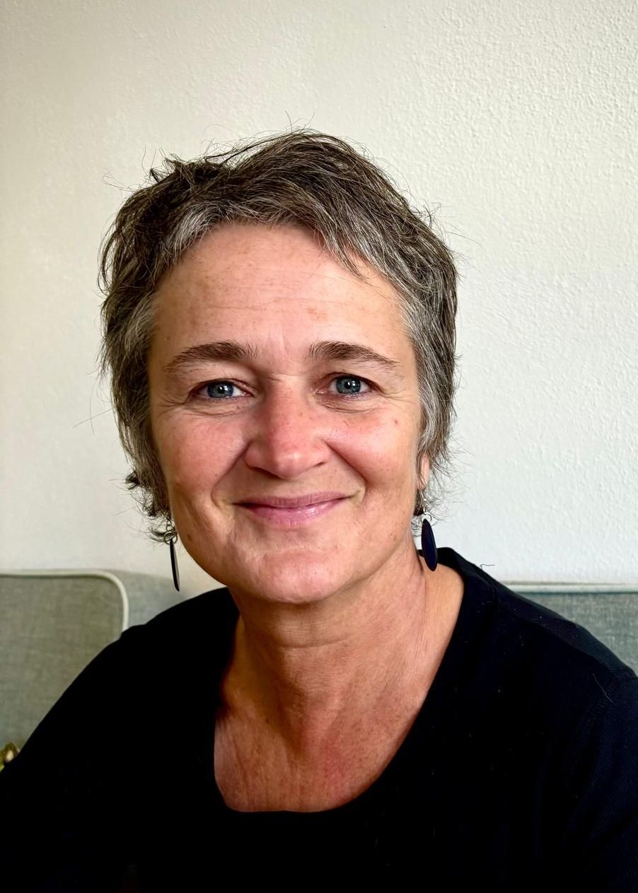 A woman is smiling for the camera while sitting on a couch.