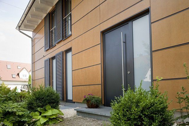 The front door of a house with a wooden facade and a black door