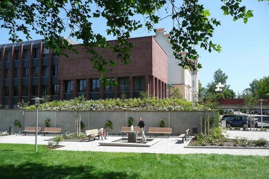 A brick building with a green roof is behind a park