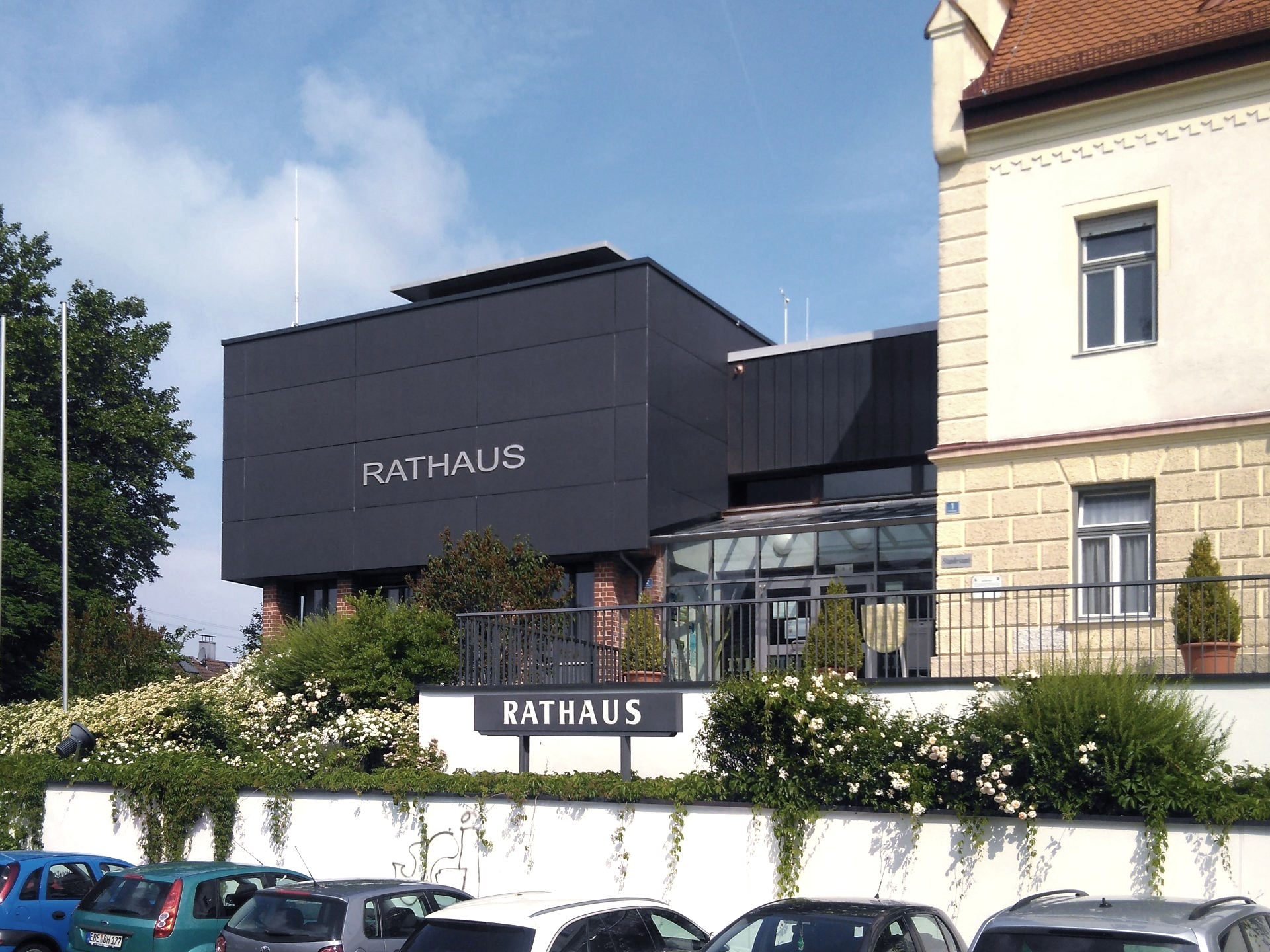 Cars are parked in front of a building that says rathaus