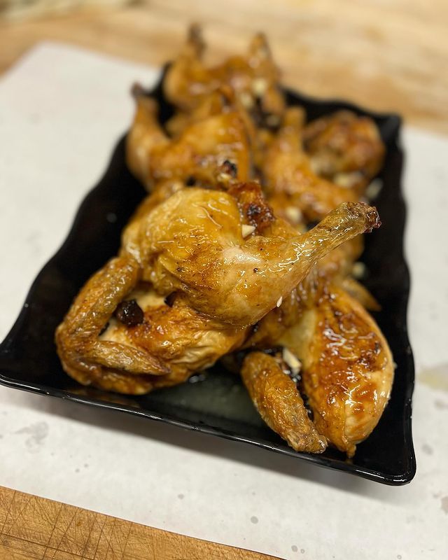 A black plate topped with fried chicken on a table.