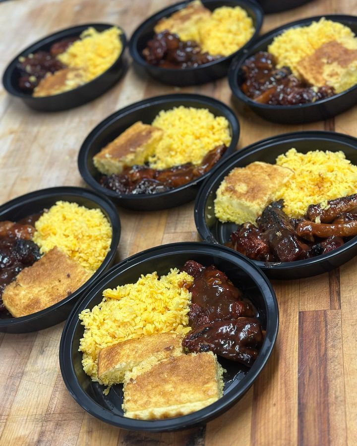 A wooden table topped with plates of food including cornbread and rice.