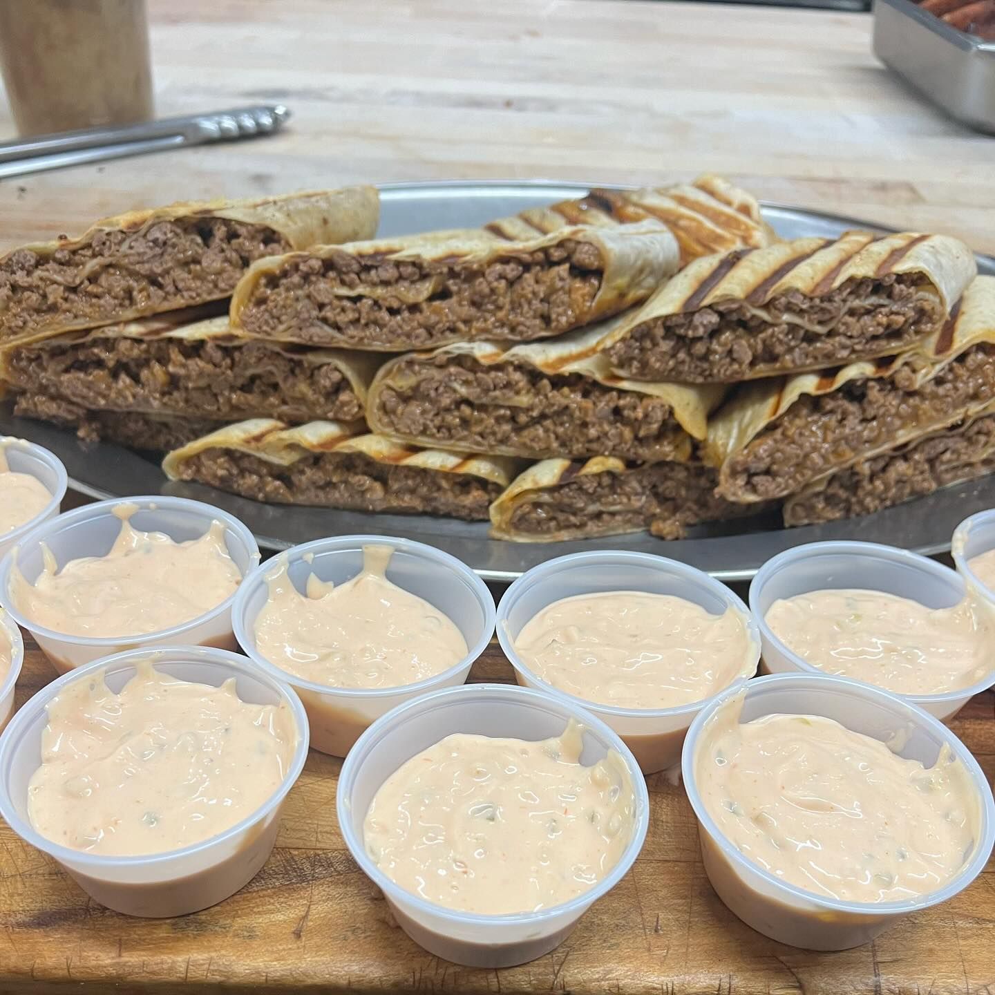 A tray of food is surrounded by small cups of sauce.