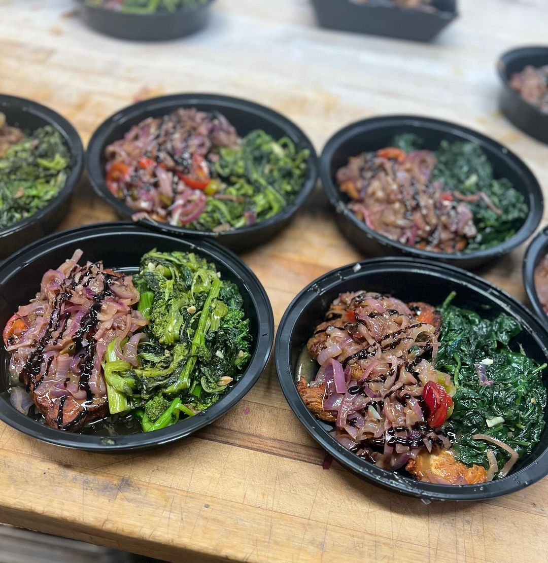 Several bowls of food are on a wooden table.